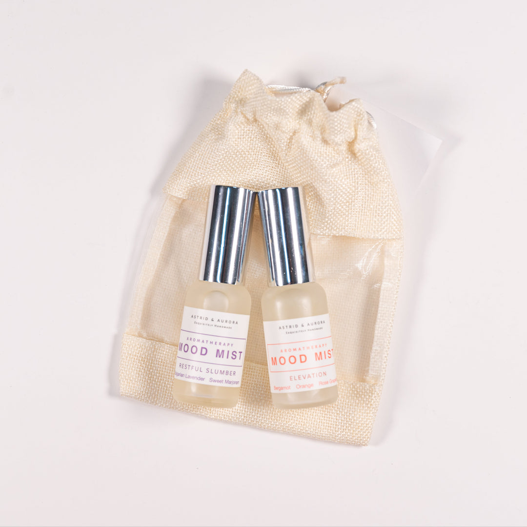 Two bottles of aromatherapy mood mists, resting on a pale canvas bag