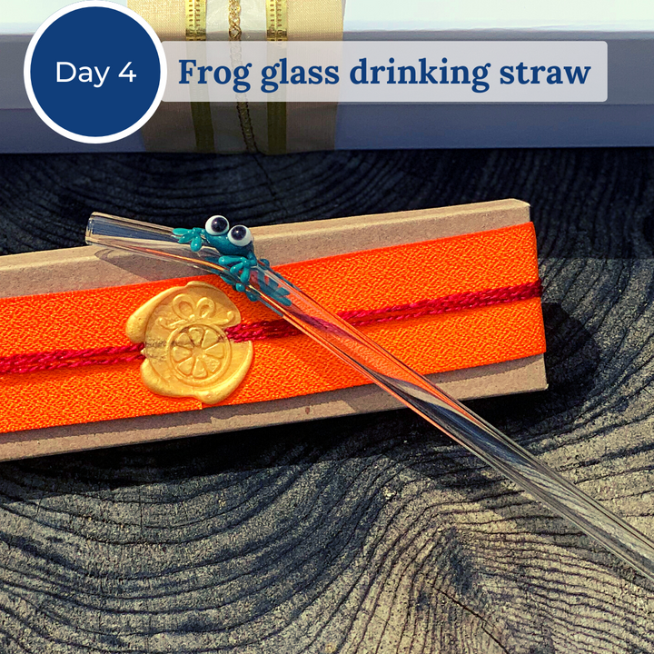 Glass drinking straw with a small green glass frog attached