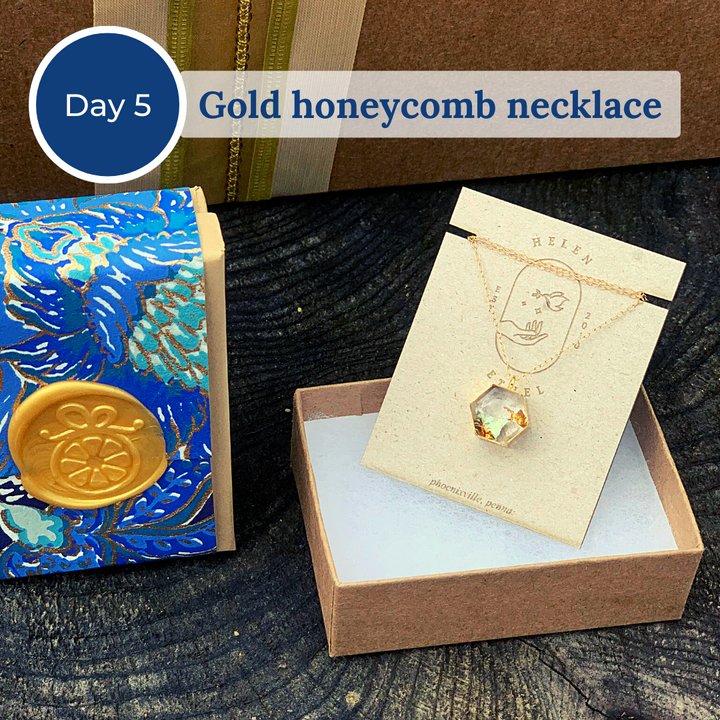 Open gift box showing a gold honeycomb necklace