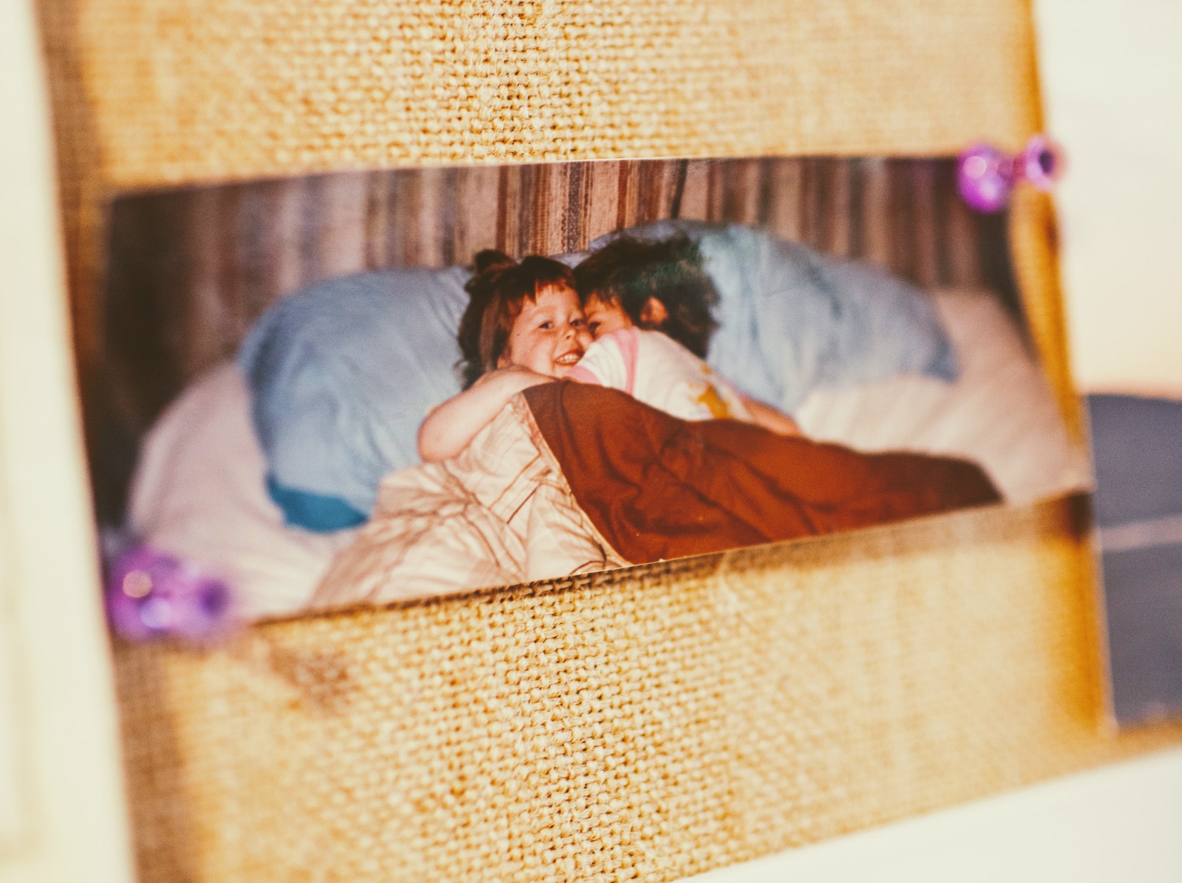 A photograph tacked on a bulletin board showing two young girls hugging