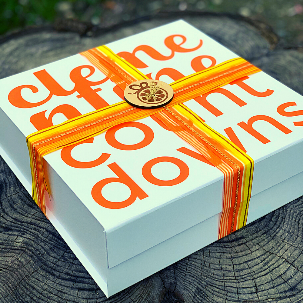 The outside of a hand-wrapped gift box with a large orange and yellow ribbon