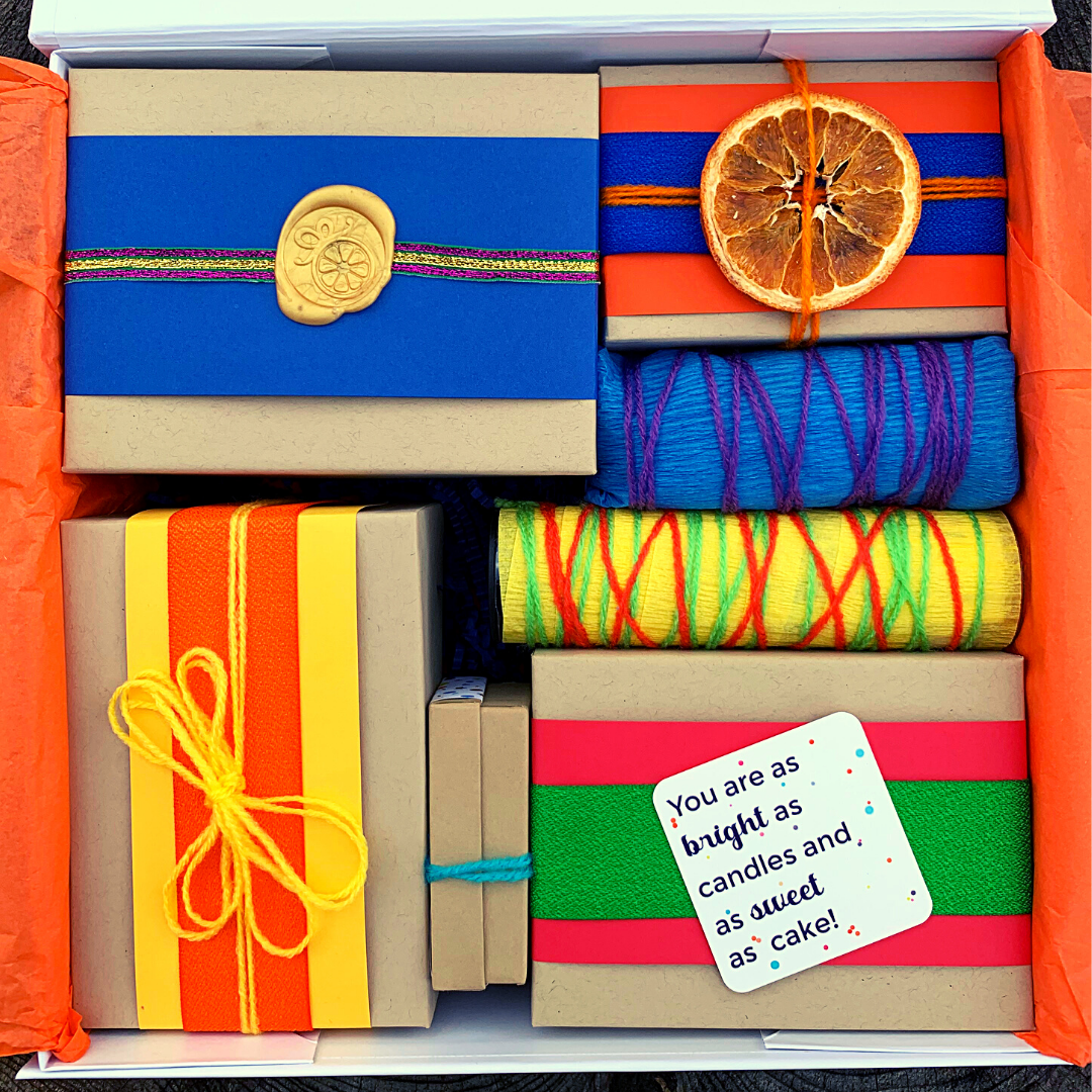 Open gift box with seven hand-wrapped gift boxes, in bright colors for children